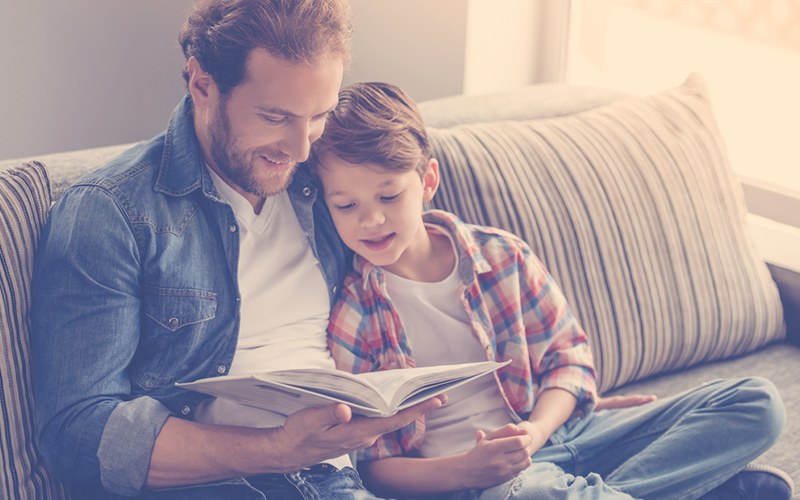 Papá leyendo junto a su hijo un libro, un plan para el dia del padre