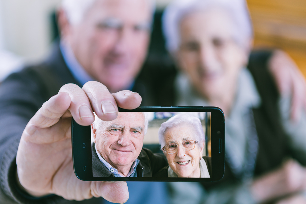 Una pareja mayor muestra una foto de autoretrato en un smartphone