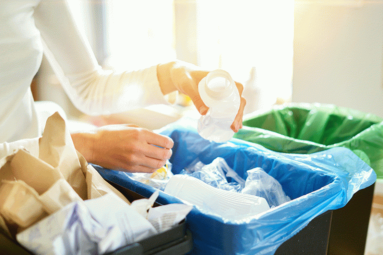 mujer poniendo botellas de plastico vacias en la papelera